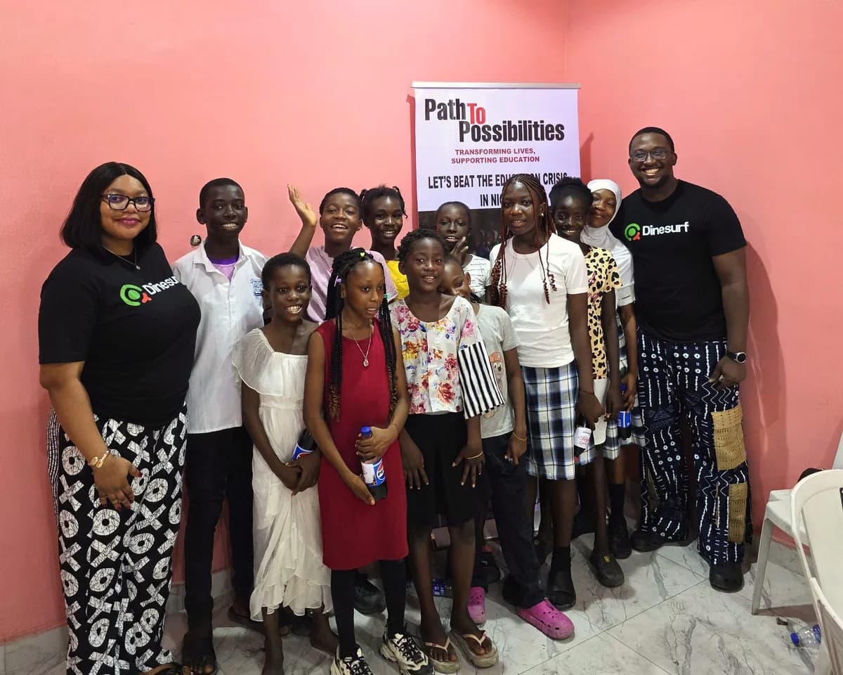 Two members of the Dinesurf team in Dinesurf T-shirts with a group of students at Path to Possibilities.