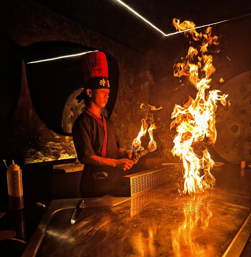 A chef cooking at the Field and Ocean teppanyaki table